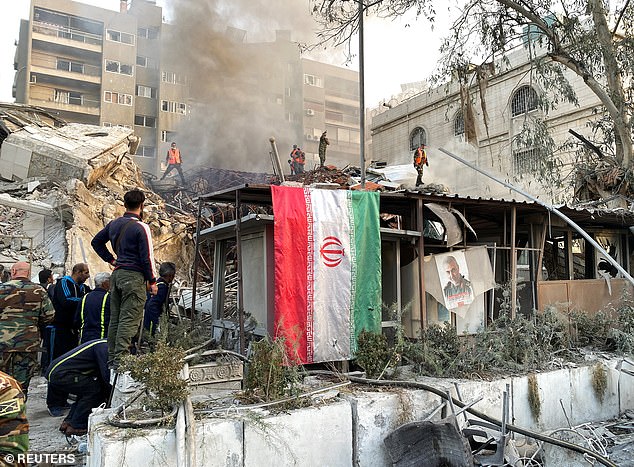 An Iranian flag is seen hanging over the bombed building, which was brought down in the attack.