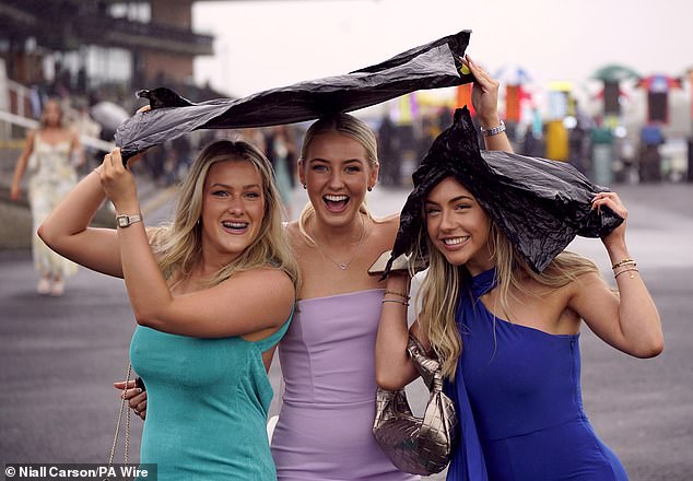A group of women were photographed with wide smiles as they tried to protect themselves from the rain with plastic bags.
