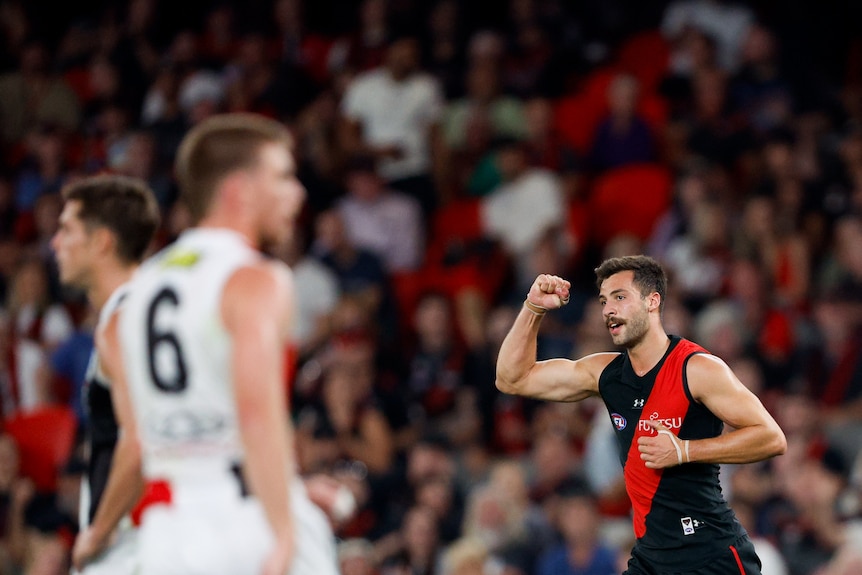 An Essendon player raised his clenched fist in celebration as a St Kilda defender looked on.