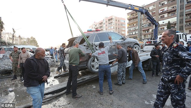 A damaged vehicle is removed after an airstrike next to the Iranian consulate in Damascus