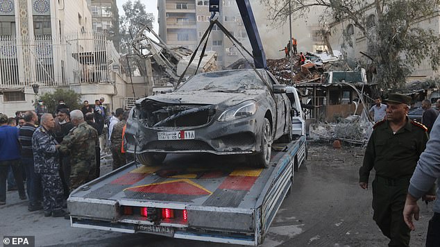 A damaged vehicle is removed following an airstrike near the Iranian consulate in Damascus on Monday.  The consulate was damaged and the adjacent building was destroyed