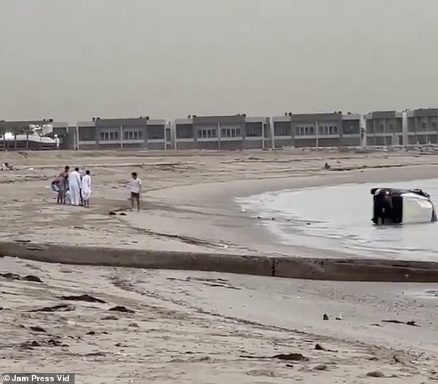 Stunned beachgoers rush to check on him and gather around as the man sits down on the sand.
