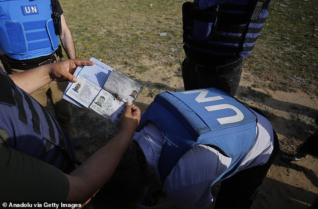 A UN worker holds James Henderson's passport at the strike site