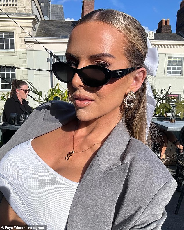Faye sunbathed at her table wearing a pair of dark sunglasses and styled her long blonde tresses into a sleek half-up updo with a white satin bow.