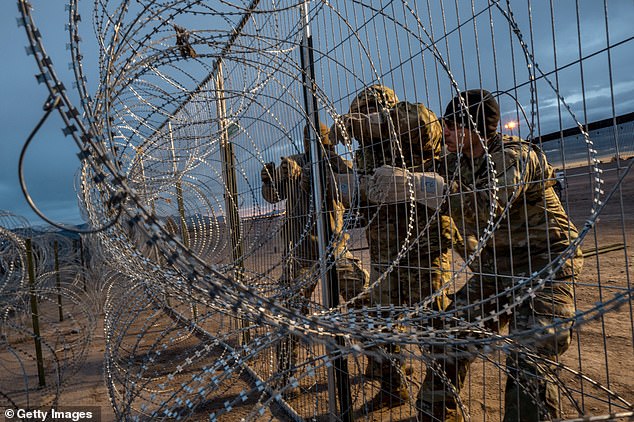 Members of the Texas National Guard install more barbed wire-covered border fencing in El Paso, Texas, on Tuesday as migrants rush toward the border barrier to gain illegal access to the U.S.