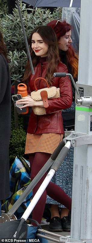 In another scene, Lily donned a burgundy leather jacket underneath with a matching dogtooth skirt.
