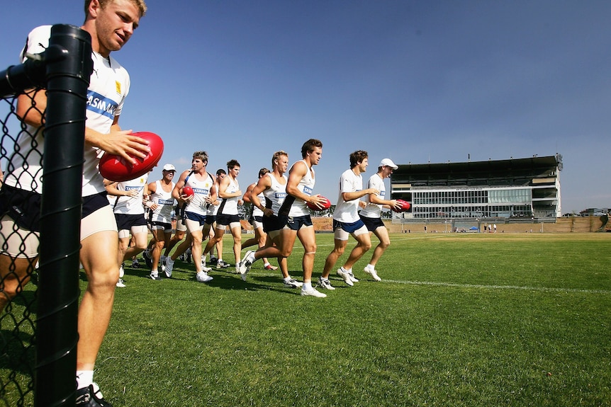 Hawthorn footballers run laps on the Waverley Park oval with the stands in the background