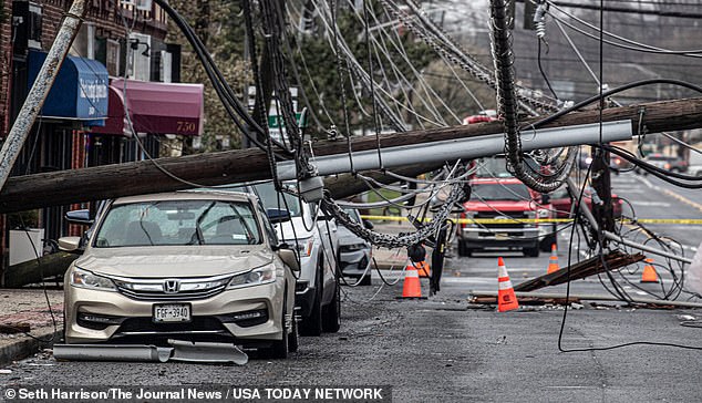 A utility pole is seen crushing several cars on Central Ave in Greenburgh, New York, on Thursday and leaving power lines dangling.