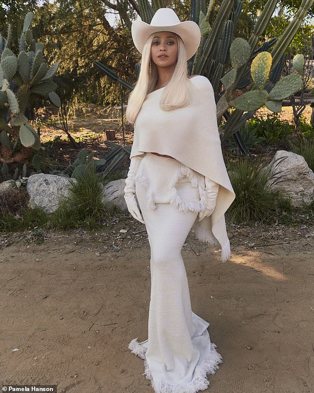 She showed off her curves in an all-white look, layering a caped blouse over a long skirt with a fringed hem and, of course, donning a matching cowboy hat.