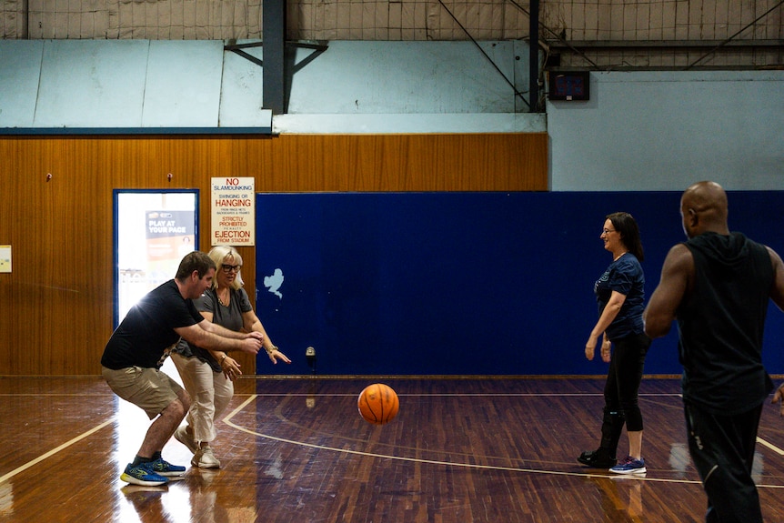 Four people on the basketball court playing basketball with visually impaired people.