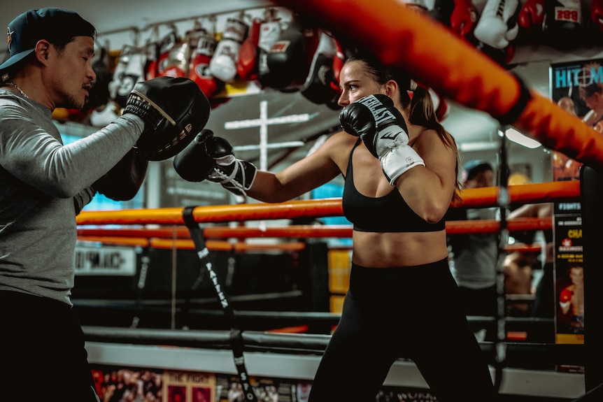 Skye Nicolson hitting pads with a trainer at a boxing camp.