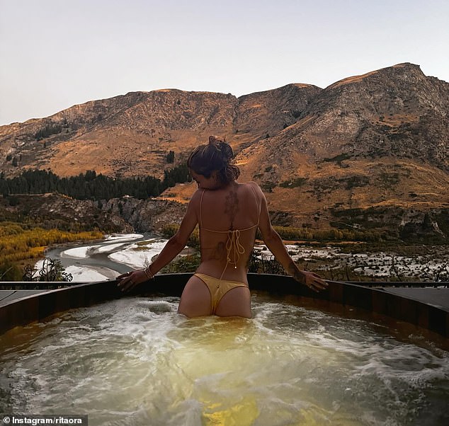 Taking to Instagram on Saturday, Rita showed off her enviable figure in a yellow swimsuit while lounging in a hot tub during a scenic mountain getaway with her sister Elena.