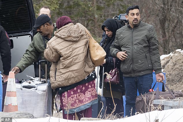 The prime minister, known for his liberal stance on immigration, said the number of temporary immigrants to Canada has more than tripled in the last seven years.  (Pictured: Asylum seekers unload their suitcases from a van while waiting to enter Canada)