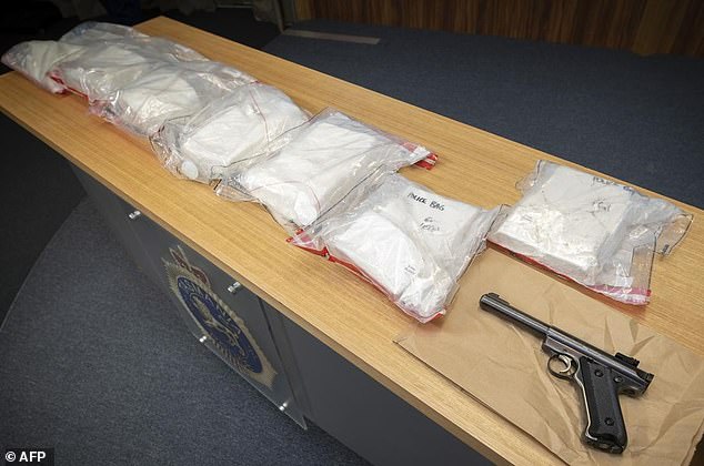 Packages of seized methamphetamine and a handgun are displayed on an evidence table.
