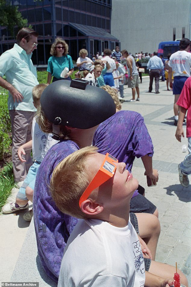 Children are seen watching the eclipse in July 1991 in Houston at the Houston Museum of Natural Sciences.  One of them is seen wearing a welding helmet to shade his eyes from the sun.