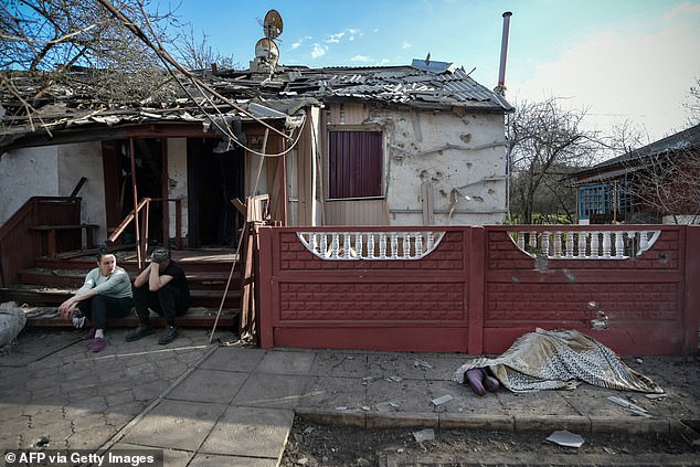 People sit in front of a house hit by a recent bombing, what local officials called a Ukrainian military strike, in Donetsk, Russian-controlled Ukraine, April 7, 2024.