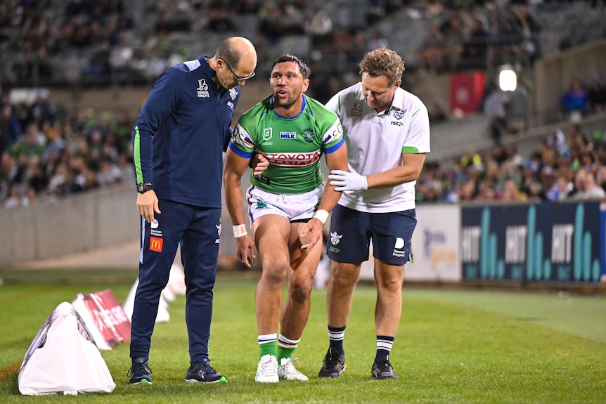 Jordan Rapana receives help from trainers after leaving a Canberra Raiders NRL game with a knee injury.