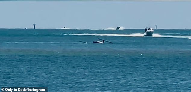 From the shore, people watched a police marine unit conduct a lightning-fast rescue; pictured: the sunk helicopter bobbing in the water and rescue boats rushing to the pilot's aid
