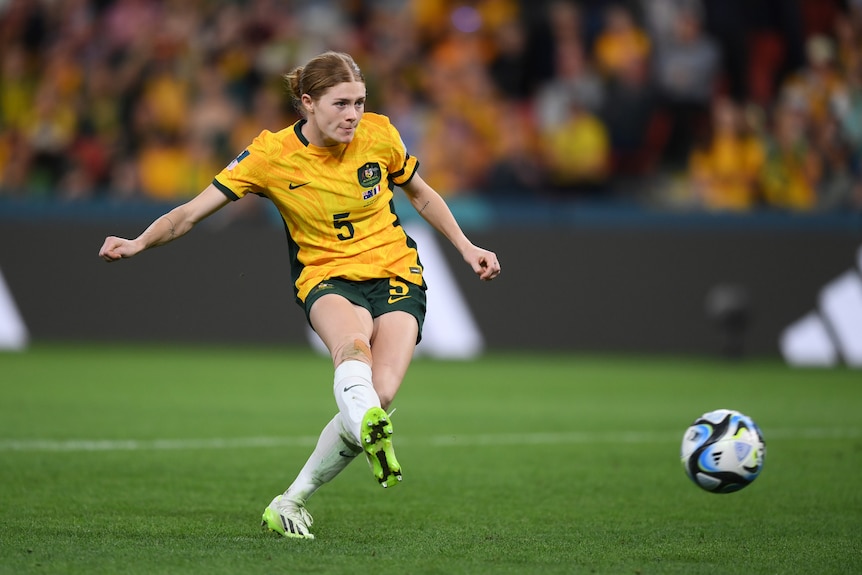 Cortnee Vine, wearing a yellow shirt and green shorts (her Matildas uniform), takes the winning penalty against France.