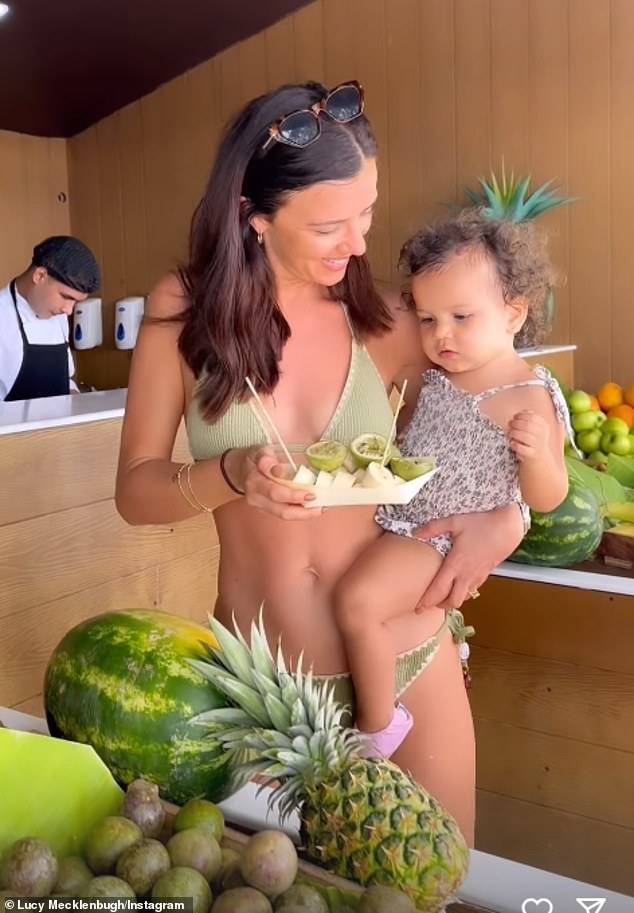 In another clip, she showed off her toned figure in a two-piece suit as she held Lilah while she enjoyed some fruit at the outdoor bar.