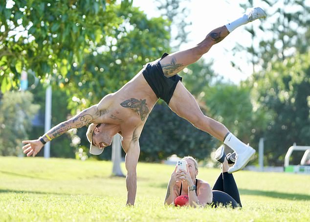 The personal trainer risked a major wardrobe malfunction when he showed off his gymnastics skills and did somersaults on the grass.