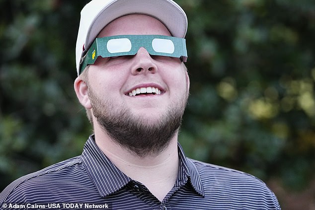 Tanner Causey, of Millbrook, Alabama, looks through eclipse glasses during a practice round for the Masters Tournament golf tournament at Augusta National Golf Club.