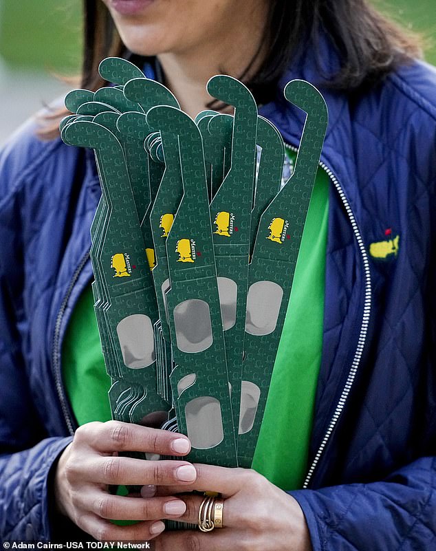 Nadine Bassalio, of Augusta, Georgia, hands out eclipse glasses during a practice round for the Masters Tournament golf tournament at Augusta National Golf Club.