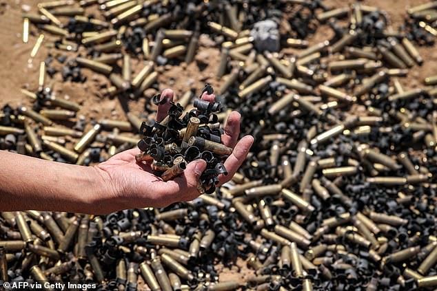 A person holds a handful of spent bullet casings over a larger pile in Khan Younis on April 7, 2024.