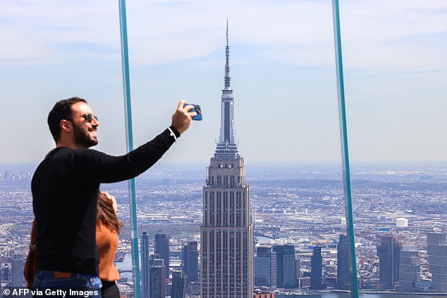 The Empire State Building is seen as a man takes a photo from the 'Edge at Hudson Yards' observation deck