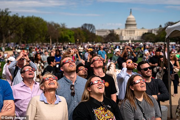 People gather on the National Mall to watch the partial solar eclipse on April 8, 2024 in Washington, DC