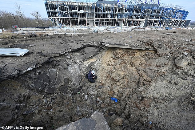 A communal worker sits in a crater after the missile attack in Kharkiv