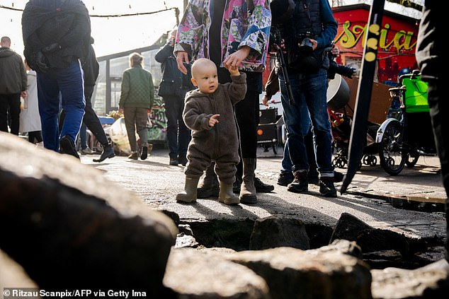 A small boy in wellies watches as locals vandalize the street of the former hippie community, which is home to around 250 children.