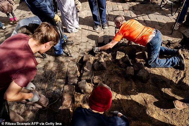 Residents of the Christiania neighborhood jointly excavate the cobblestones of Pusher Street