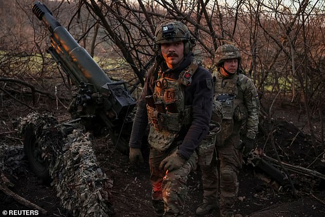 Servicemen of the 12th Azov Special Forces Brigade of the National Guard of Ukraine stand near a howitzer on the front