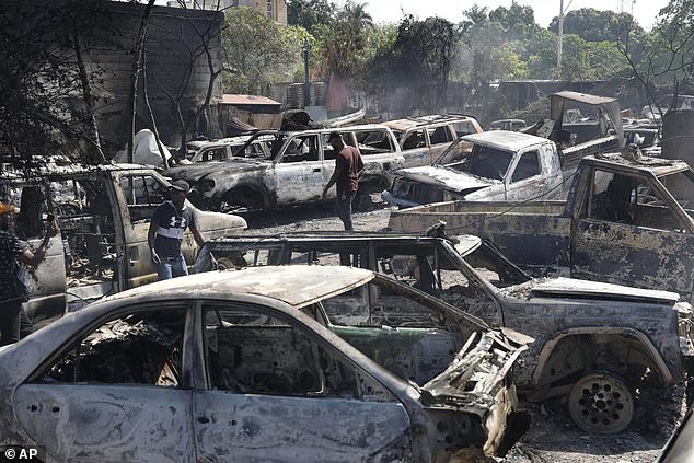 People search for salvageable parts from burned cars at a mechanic shop set on fire during armed gang violence in Port-au-Prince, Haiti, Monday, March 25, 2024.