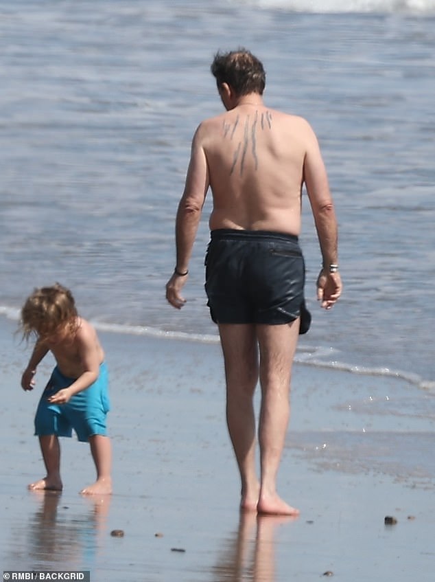 The First Son was wearing a black swimsuit and was shirtless, proudly displaying his striking back tattoo.