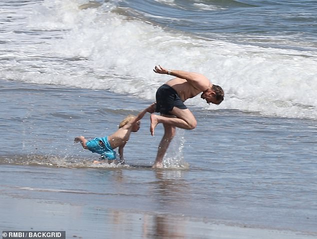 Hunter seemed unconcerned, playfully pulling his son into the waves while almost face-planting.
