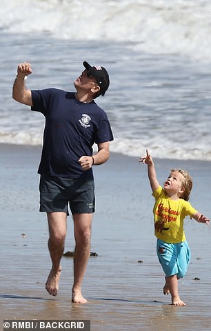 Later, Hunter covered up in a t-shirt and cap, ran down the beach and looked up with the adorable Beau.