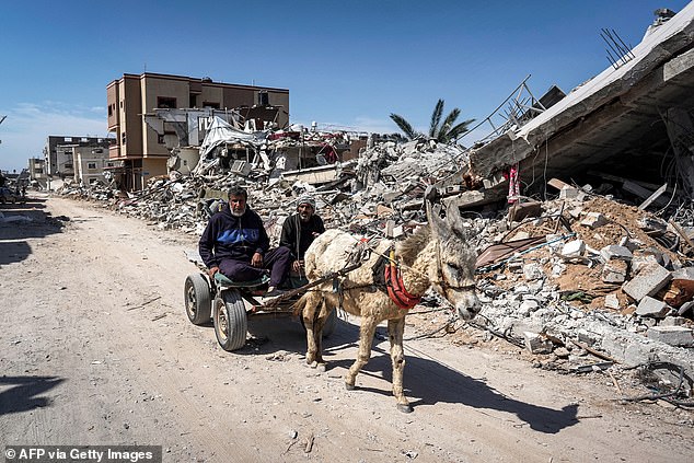 Two men sitting on a donkey cart pass through the rubble of a destroyed building in Khan Yunis on April 7, 2024, after Israel withdrew its ground forces from the southern Gaza Strip, six months after the devastating war caused by the attacks of October 7.