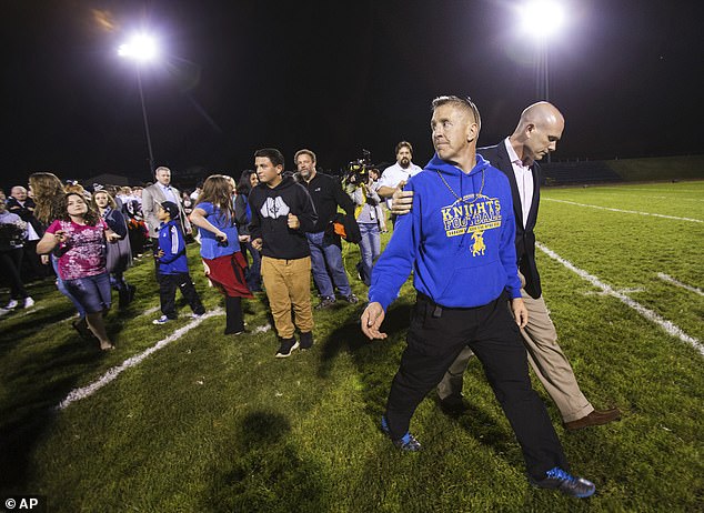 Bremerton High assistant football coach Joe Kennedy, front, walks off the field with his attorney, right, on Oct. 16, 2015, after praying at the 50-yard line following a football game in Bremerton , Washington.