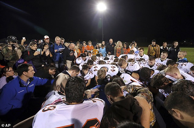 Joe Kennedy is surrounded by Centralia High School football players as they kneel and pray with him on the field after their game in 2015.