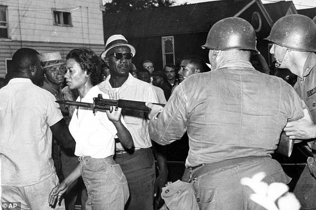 Gloria Richardson, head of the Cambridge Nonviolent Action Committee, pushes aside a National Guardsman's bayonet as she moves through a crowd of African Americans to convince them to disperse in Cambridge, Maryland.