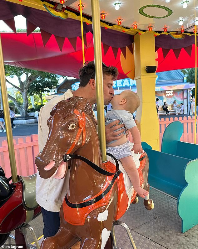 Ryan kisses his son while the little one takes a ride on a carousel.