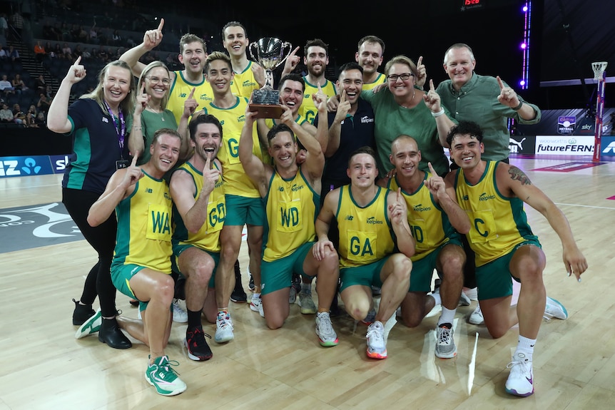 The Australian men's team dressed in green and gold pose together as the captain places the trophy aloft.