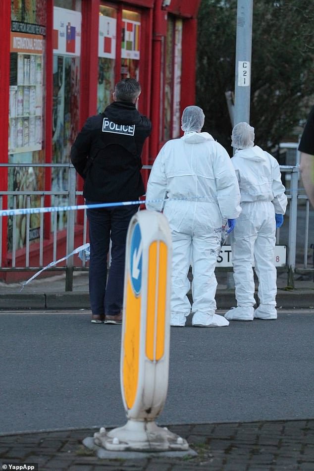 Police officers in white forensic equipment stand inside a cordon at the scene of the stabbing in Bradford.