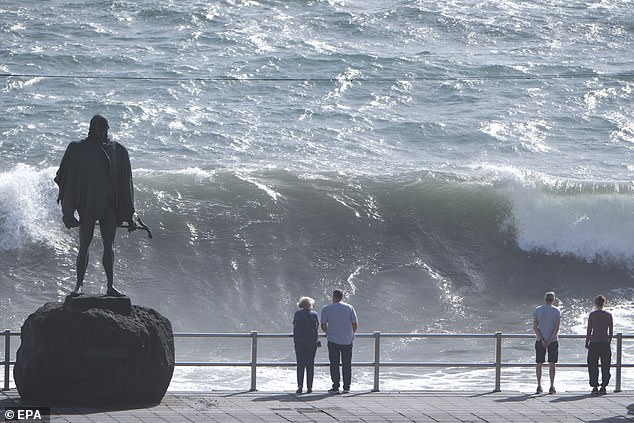The person who died, a 53-year-old Czech tourist, fell into rough seas in the northern town of Puerto de la Cruz and drowned despite efforts to save him.  Pictured: People watch the high waves arriving in Candelaria, Tenerife, on Wednesday.