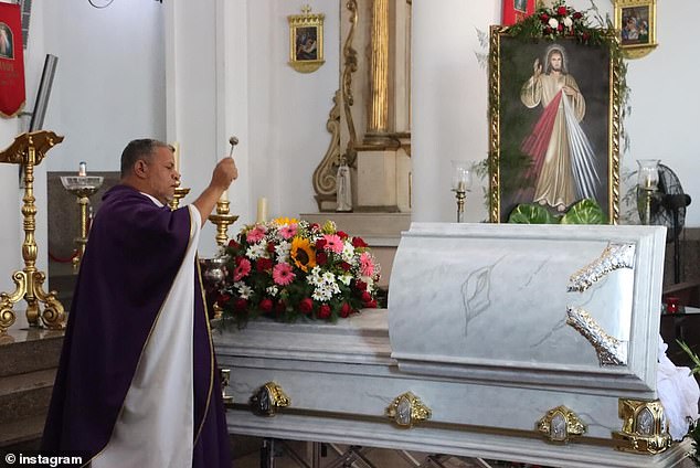 A priest at the Cathedral of Saint Peter the Apostle sprinkles holy water on Wilevis Brito's coffin on Wednesday.
