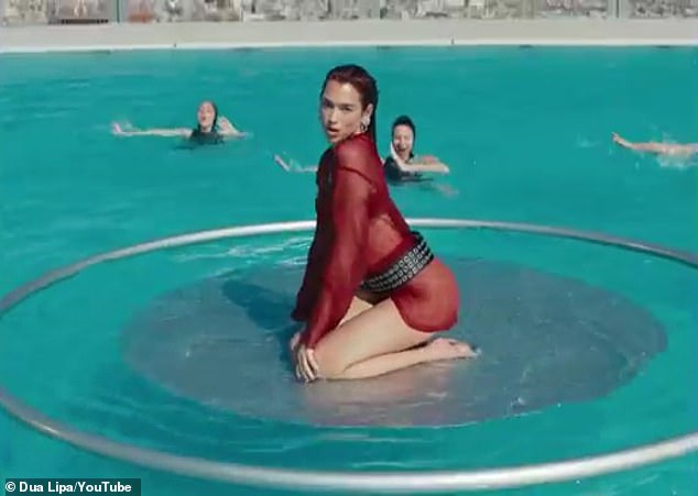 The 28-year-old English and Albanian singer was photographed writhing on a platform in the middle of a large pool, surrounded by a circle of synchronized swimmers.