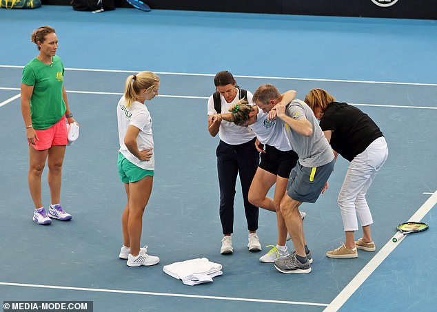 Hunter receives assistance from the court as captain Sam Stosur and teammate Daria Saville look on.