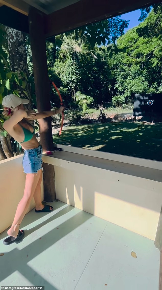 Carrie is shown at the beginning of the video aiming at the archery target with her arrow sticking out of the yellow inner circle.  Beaming with pride, the former The Project host also showed off her stunning assets in a green bikini top and denim shorts.